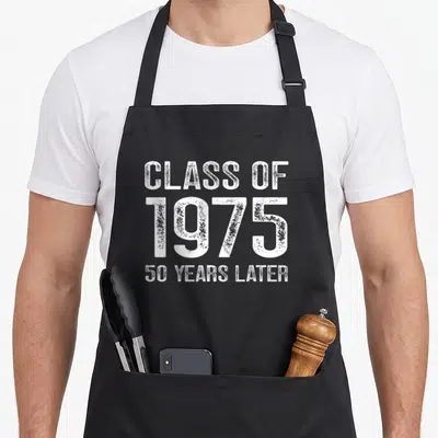 Class homecoming apron - White distressed text reading CLASS OF 1975 50 YEARS LATER in three stacked lines — shown on a black cotton canvas apron against a white background