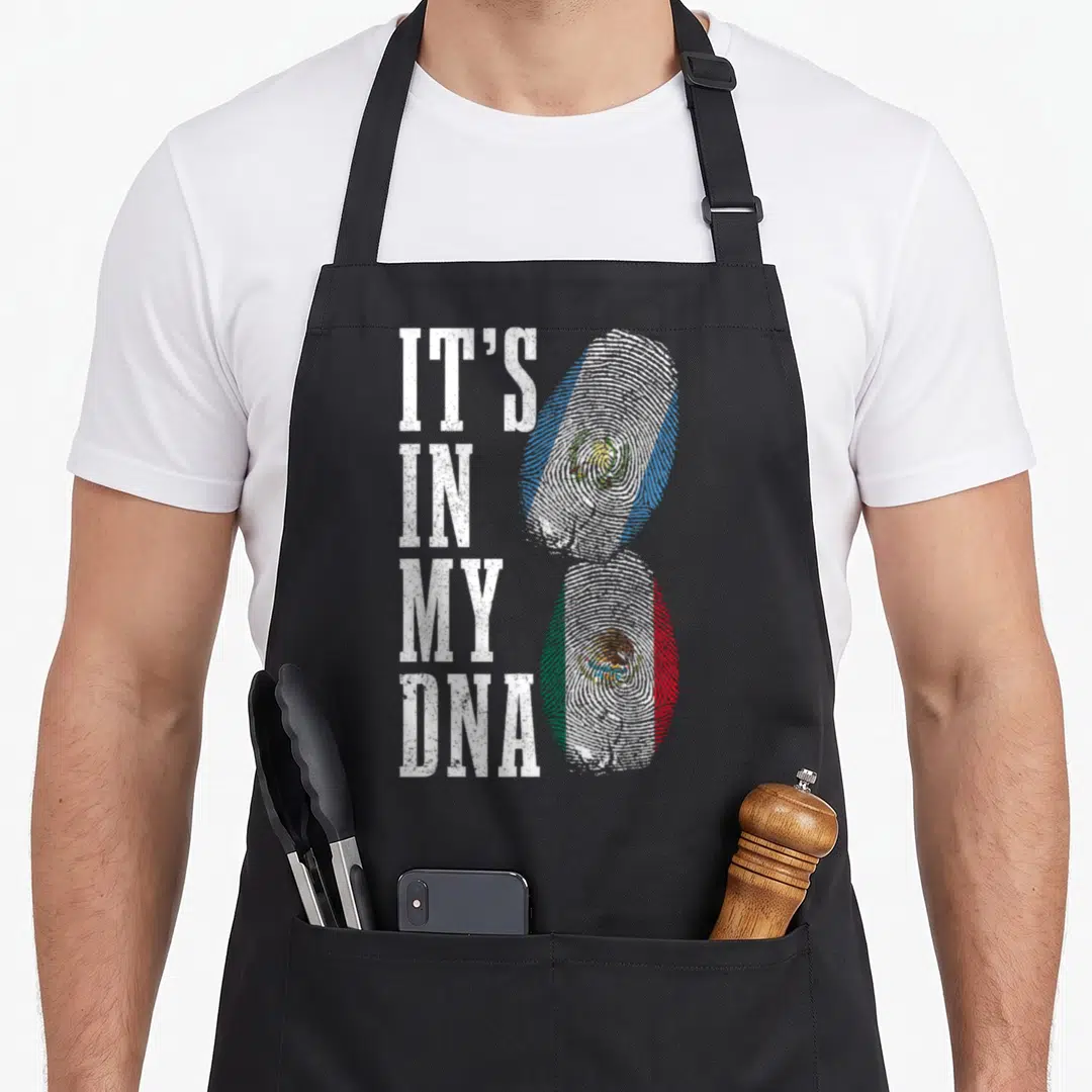 Guatemala mexico apron - IT'S IN MY DNA text next to two fingerprints filled with Guatemalan and Mexican flag colors — shown on a black cotton canvas apron against a white background
