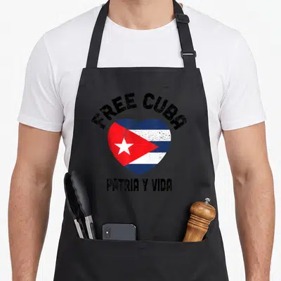 Patria vida cuba libre apron - Distressed heart with Cuban flag and text FREE CUBA PATRIA Y VIDA — shown on a black cotton canvas apron against a white background