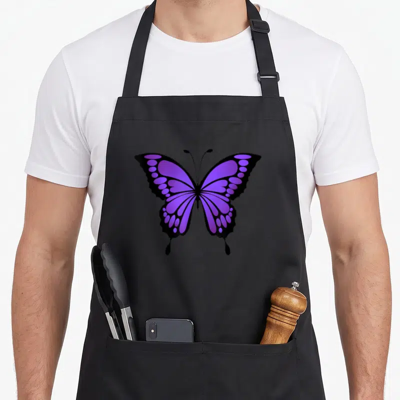 Vibrant butterfly apron - Purple and black cartoon butterfly graphic centered on an apron front — shown on a black cotton canvas apron against a white background