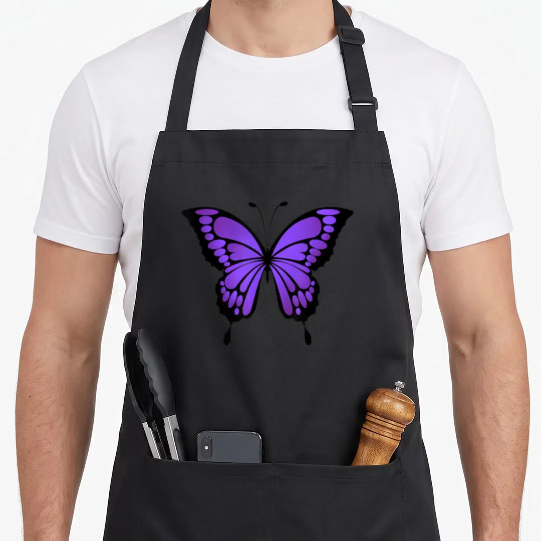 Vibrant butterfly apron - Purple and black cartoon butterfly graphic centered on an apron front — shown on a black cotton canvas apron against a white background