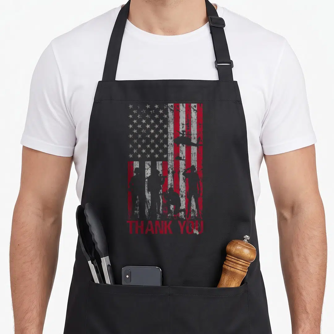 Memorial american flag apron - Distressed red and grey flag with soldier silhouettes and THANK YOU text — shown on a black cotton canvas apron against a white background