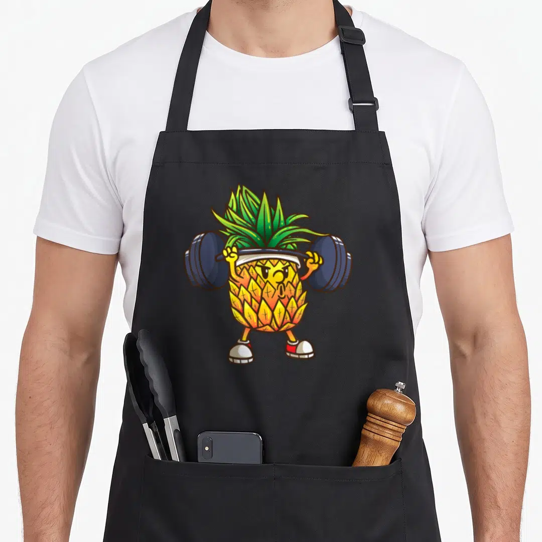 Powerlifting pineapple apron - Cartoon pineapple character lifting a dark blue barbell wearing sneakers and a white — shown on a black cotton canvas apron against a white background