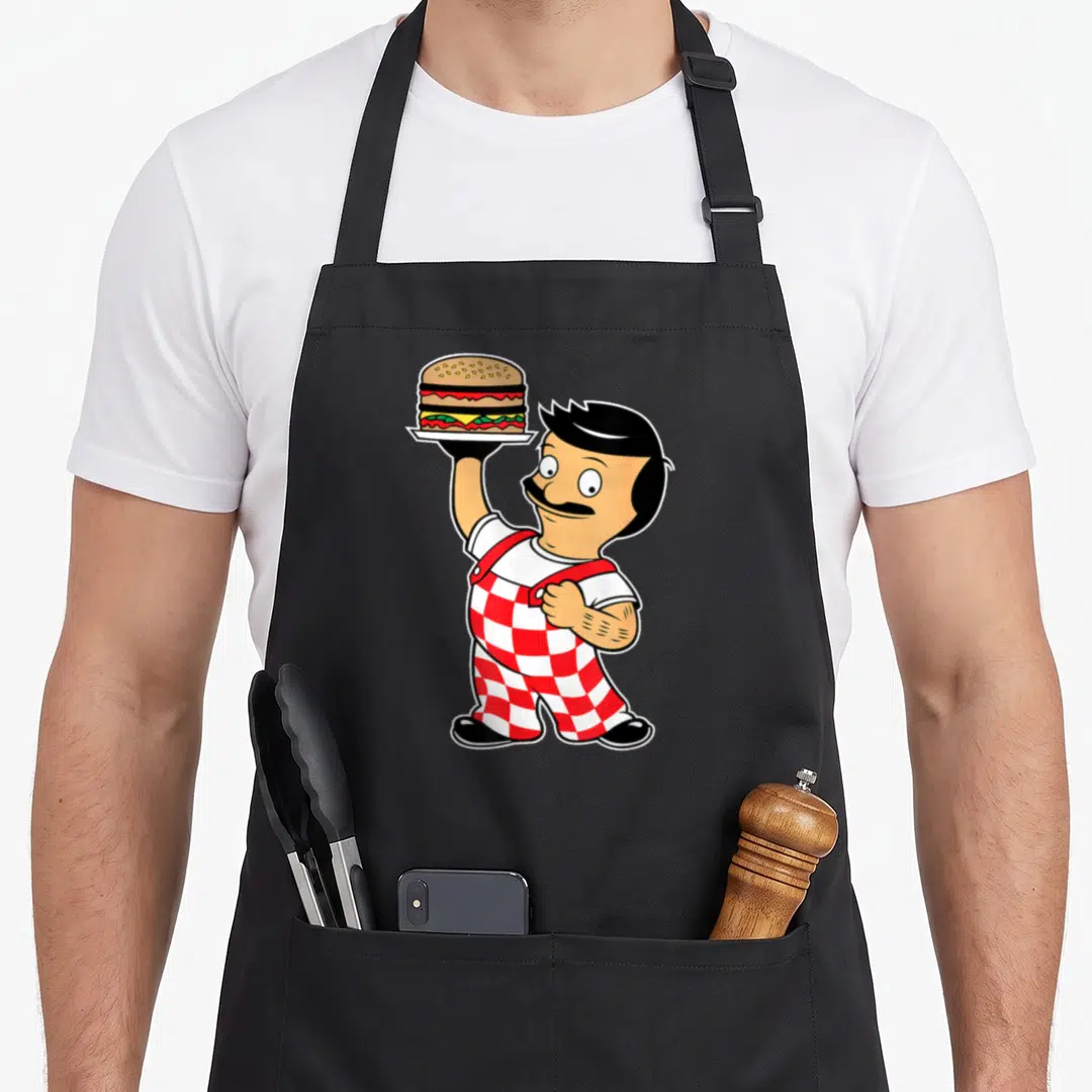 Funny bob bobsled apron - Cartoon chef in red checkered pants holding a burger on a plate — shown on a black cotton canvas apron against a white background