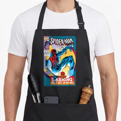 Cute comic cover apron - Spider-Man 2099 comic cover print with warning text and skull icon on black fabric — shown on a black cotton canvas apron against a white background