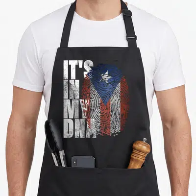 Dna hispanic aprons - Distressed fingerprint with white red blue flag pattern next to stacked IT'S IN MY DNA text — shown on a black cotton canvas apron against a white background