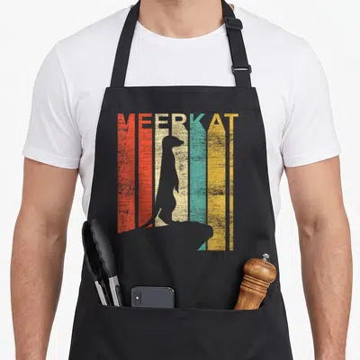 Cute meerkat apron - Grey meerkat silhouette on red orange beige teal and yellow vertical stripes with MEERKAT text — shown on a black cotton canvas apron against a white background