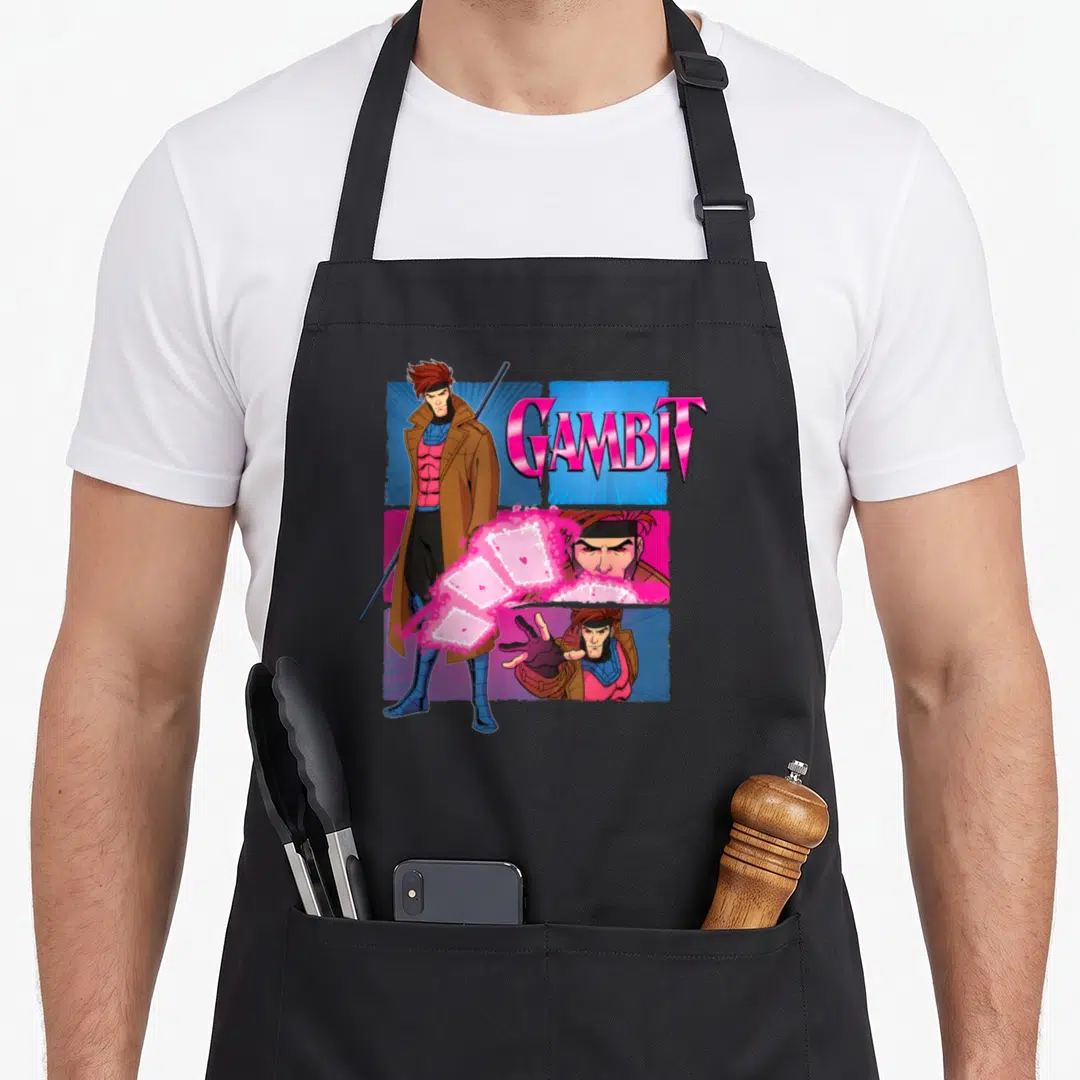 Studio x apron - Gambit cartoon figure with pink blue brown panels and glowing cards — shown on a black cotton canvas apron against a white background