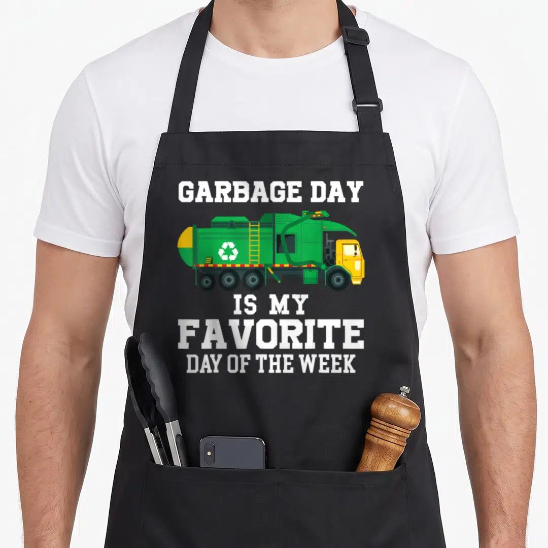 Garbage trash truck apron - Green cartoon garbage truck with white text GARBAGE DAY IS MY FAVORITE DAY OF THE WEEK — shown on a black cotton canvas apron against a white background