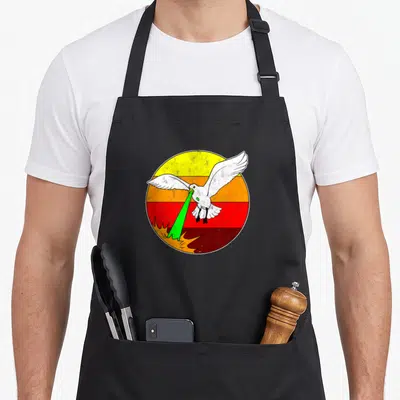Laser 80s apron - White seagull firing green laser over yellow orange red striped circle — shown on a black cotton canvas apron against a white background