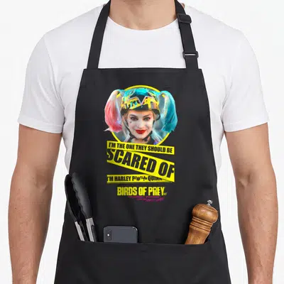 Bird vehicle apron - Harley Quinn helmet photo with yellow caution tape reading I'm the one they should be scared — shown on a black cotton canvas apron against a white background