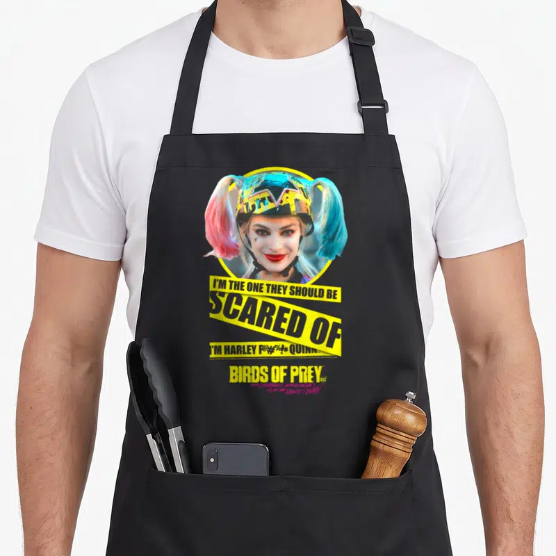 Bird vehicle apron - Harley Quinn helmet photo with yellow caution tape reading I'm the one they should be scared — shown on a black cotton canvas apron against a white background