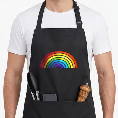 Rainbow stripe apron - Single rainbow arc with red orange yellow green blue purple bands on black background — shown on a black cotton canvas apron against a white background