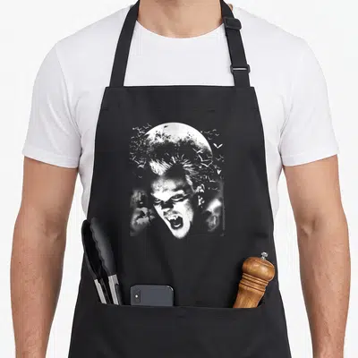 Lost david aprons - Distressed white vampire face centered before moon with scattered bats and clouds — shown on a black cotton canvas apron against a white background