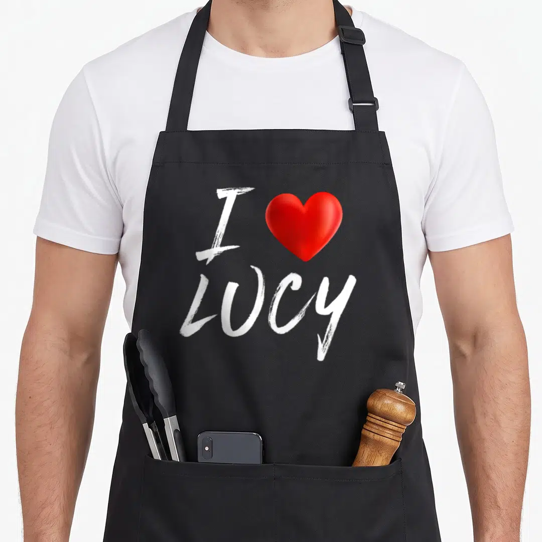 Family i love lucy apron - White I and LUCY text with a red heart symbol — shown on a black cotton canvas apron against a white background