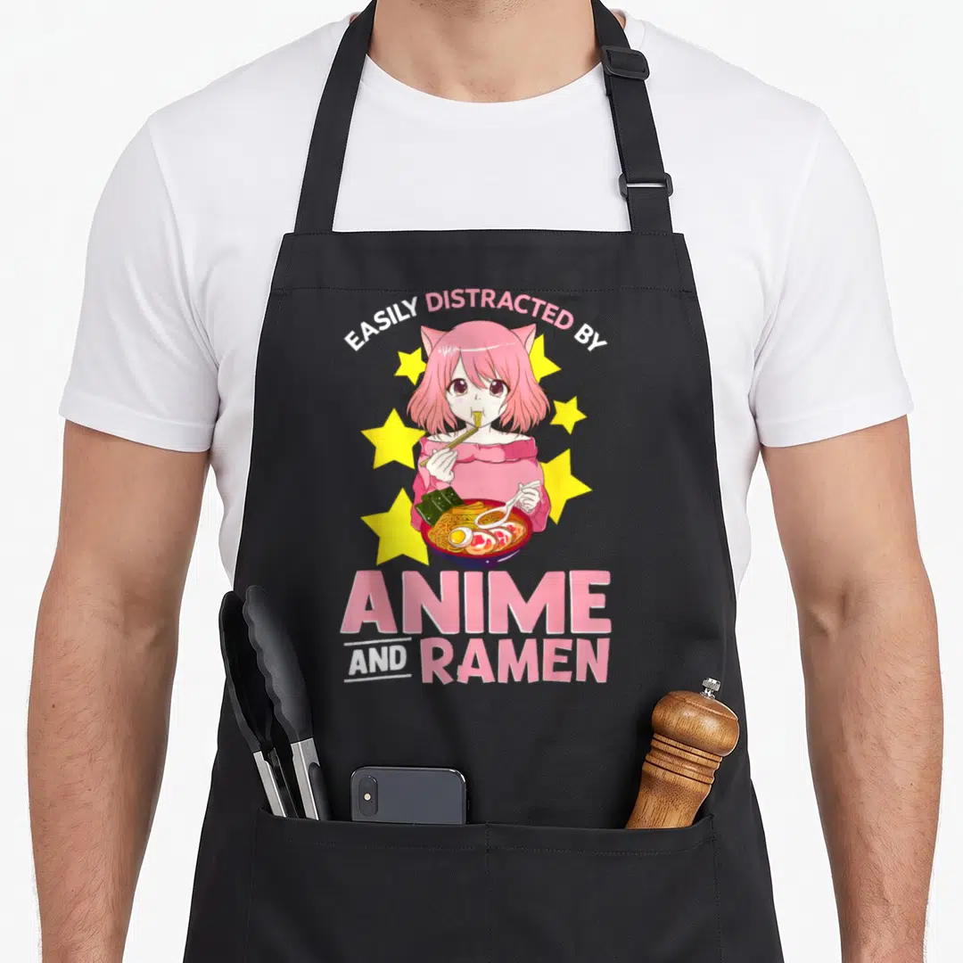 Easily anime apron - Pink haired anime girl eating ramen with stars and text EASILY DISTRACTED BY ANIME AND RAMEN — shown on a black cotton canvas apron against a white background
