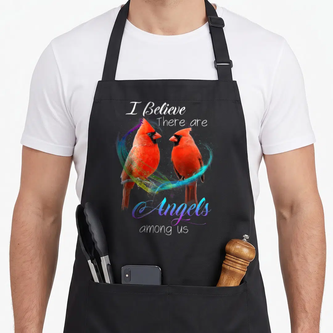 Bird cardinal apron - Two red cardinals on a branch with text I Believe There are Angels among us surrounded — shown on a black cotton canvas apron against a white background