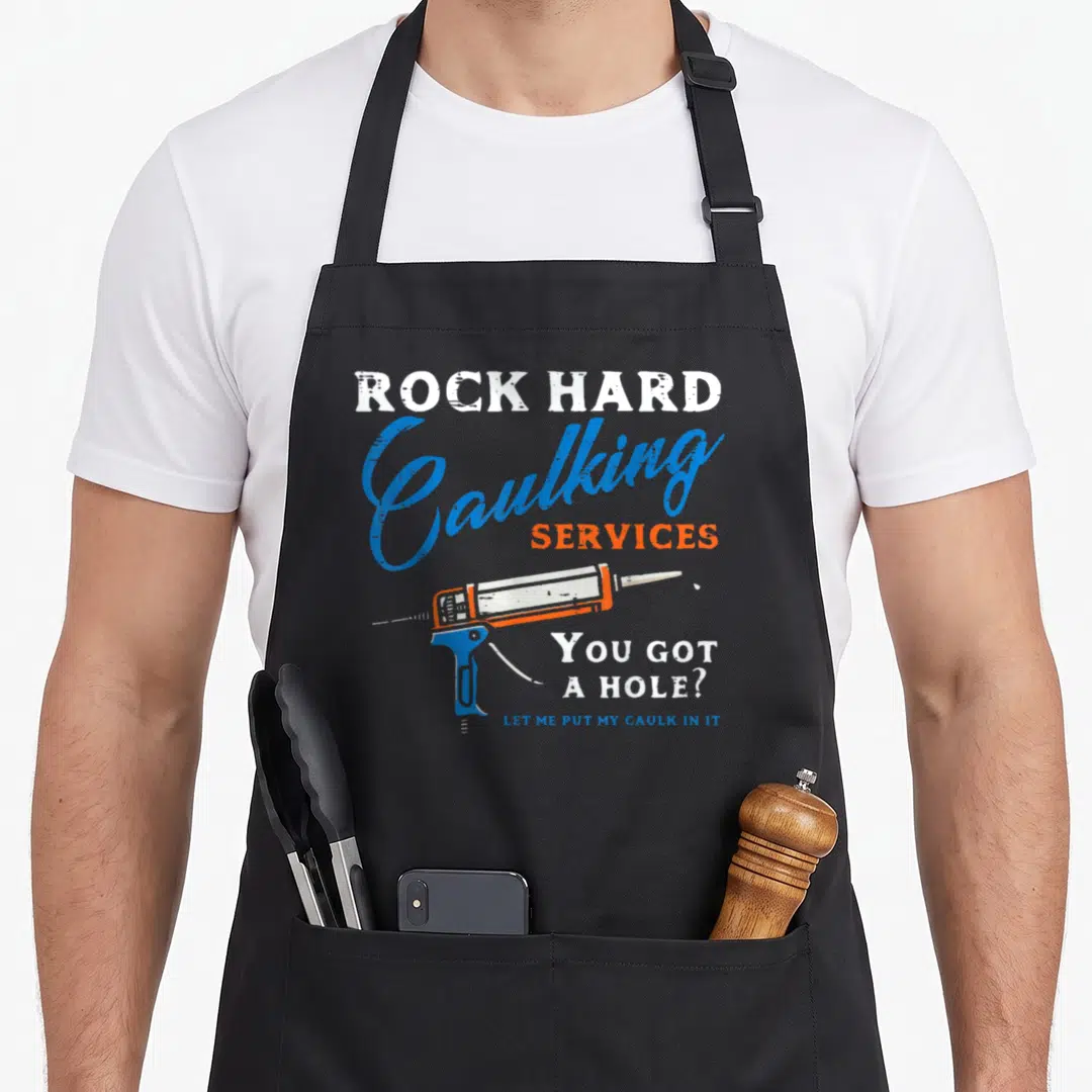 Rock service apron - ROCK HARD Caulking SERVICES text with caulking gun and You Got A Hole pun in blue orange white — shown on a black cotton canvas apron against a white background