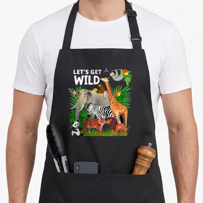 Zoo animal wildlife birthday apron - Cartoon jungle animals with LET'S GET WILD text and tropical leaves — shown on a black cotton canvas apron against a white background