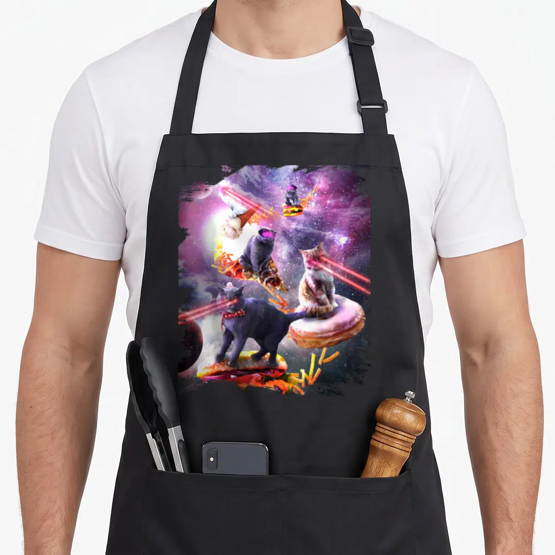 Galaxy ice cream apron - Four cats perched on burger pizza doughnut ice cream with laser eyes in purple space — shown on a black cotton canvas apron against a white background