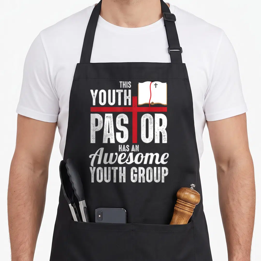 Youth pastor christian apron - Red cross overlaps white text reading This Youth Pastor Has An Awesome Youth Group next — shown on a black cotton canvas apron against a white background
