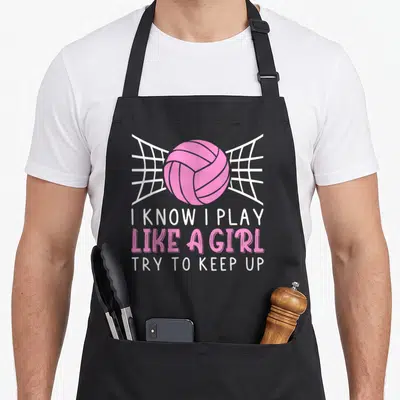 Vintage player volleyball apron - Pink volleyball over white net with text I KNOW I PLAY LIKE A GIRL TRY TO KEEP UP — shown on a black cotton canvas apron against a white background