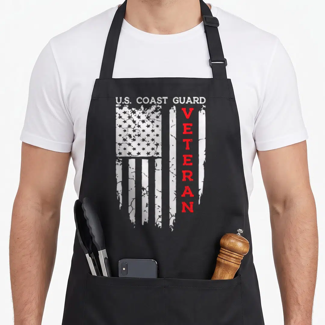 Coast american flag apron - Distressed US flag with vertical red VETERAN text and white U.S. COAST GUARD header — shown on a black cotton canvas apron against a white background
