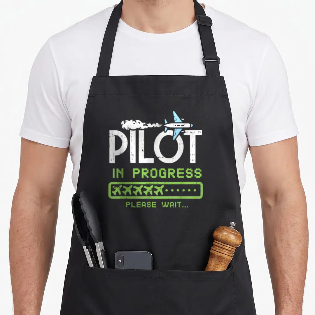Progress airplane apron - Cartoon airplane above PILOT text with lime green loading bar and dots — shown on a black cotton canvas apron against a white background