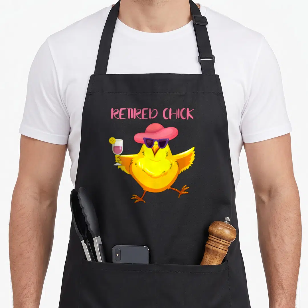 Grandma retirement apron - Cartoon yellow chick with pink hat and purple sunglasses holding cocktail under Retired — shown on a black cotton canvas apron against a white background