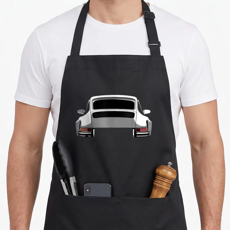 Legendary racing car apron - Rear view of a white sports car with black grille and red taillights on grey background — shown on a black cotton canvas apron against a white background