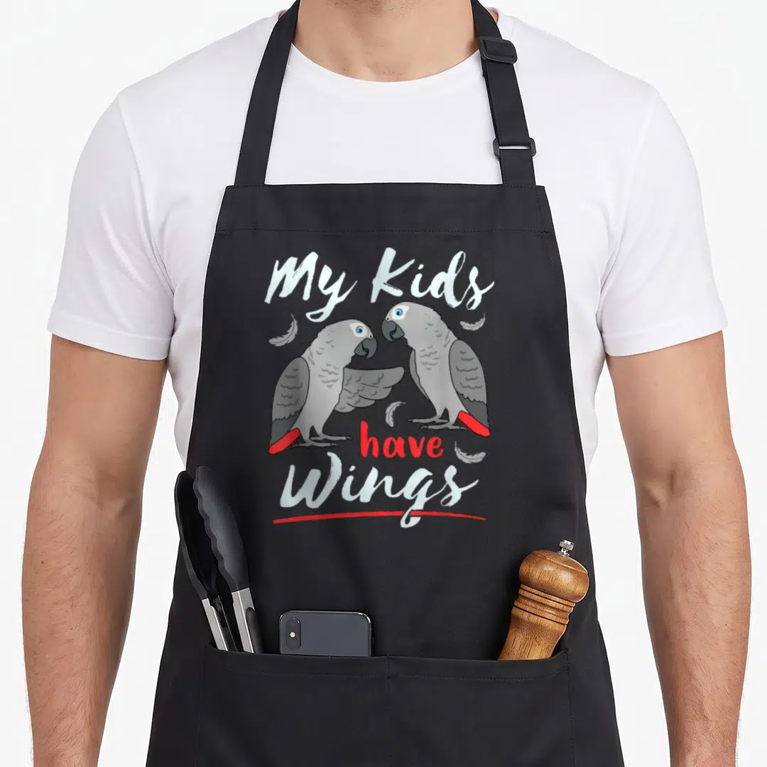 African parrot bird apron - Two grey parrots facing each other with red tails and text My Kids have Wings — shown on a black cotton canvas apron against a white background