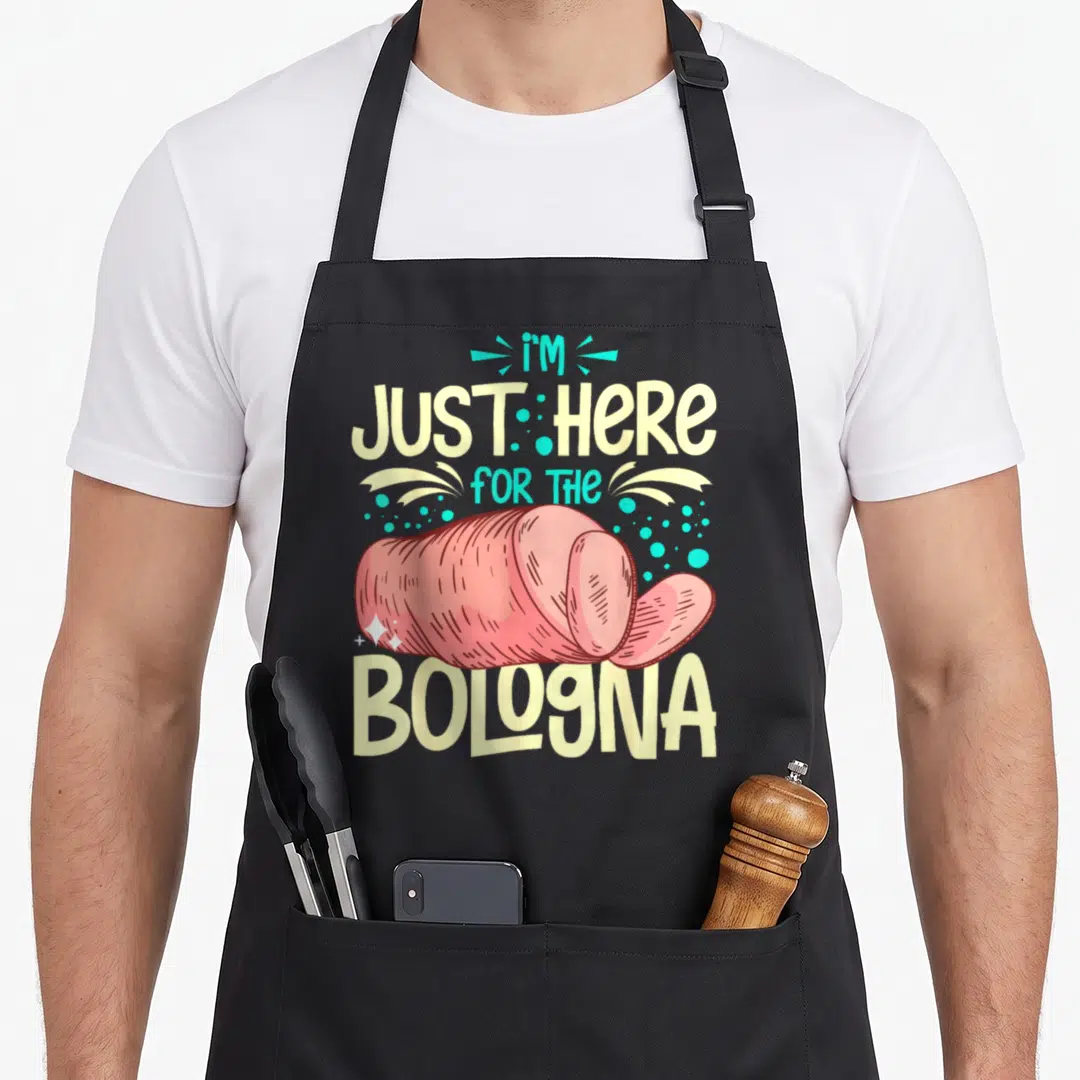 Bologna meat aprons - Pink cartoon bologna log slice with pale yellow and turquoise text and scattered dots — shown on a black cotton canvas apron against a white background