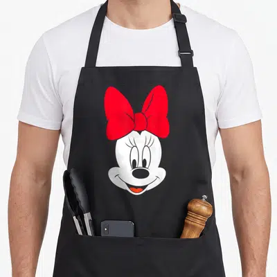 Funny face apron - White cartoon mouse head with large red bow and grey outlines on grey background — shown on a black cotton canvas apron against a white background