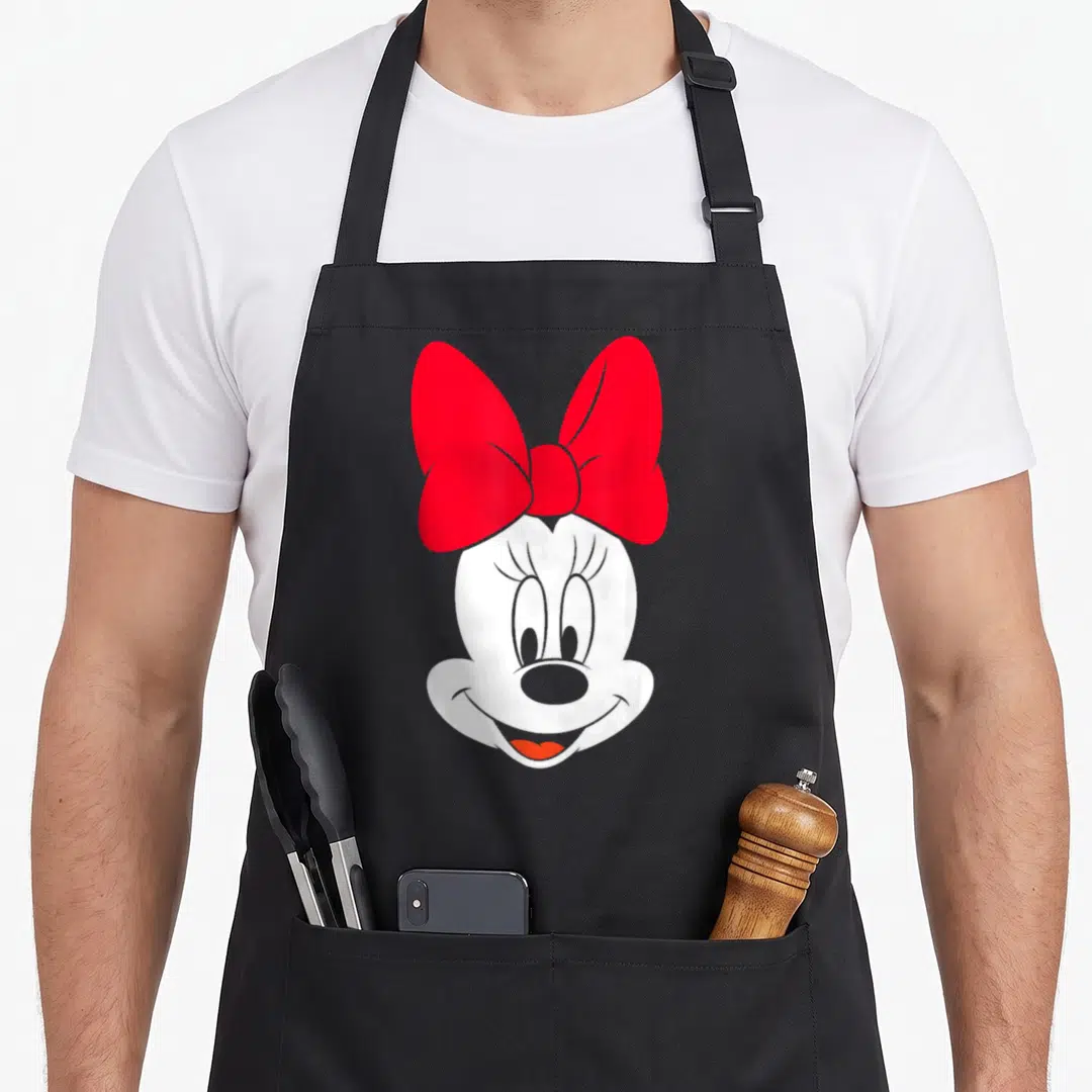 Funny face apron - White cartoon mouse head with large red bow and grey outlines on grey background — shown on a black cotton canvas apron against a white background
