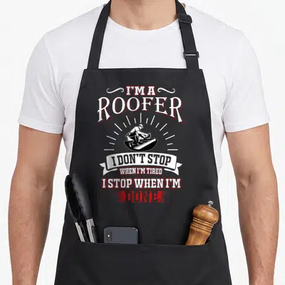 Tired roofer apron - Stacked text I'm a Roofer I Don't Stop When I'm Tired surrounding a roofer illustration — shown on a black cotton canvas apron against a white background
