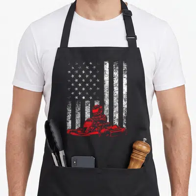 Kart american flag apron - Distressed white American flag background with red go-kart driver silhouette in foreground — shown on a black cotton canvas apron against a white background