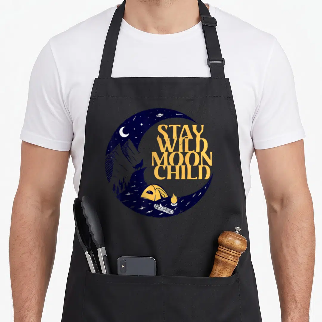 Peace boho apron - Stay Wild Moon Child text inside blue crescent moon with wolf, tent, and campfire — shown on a black cotton canvas apron against a white background