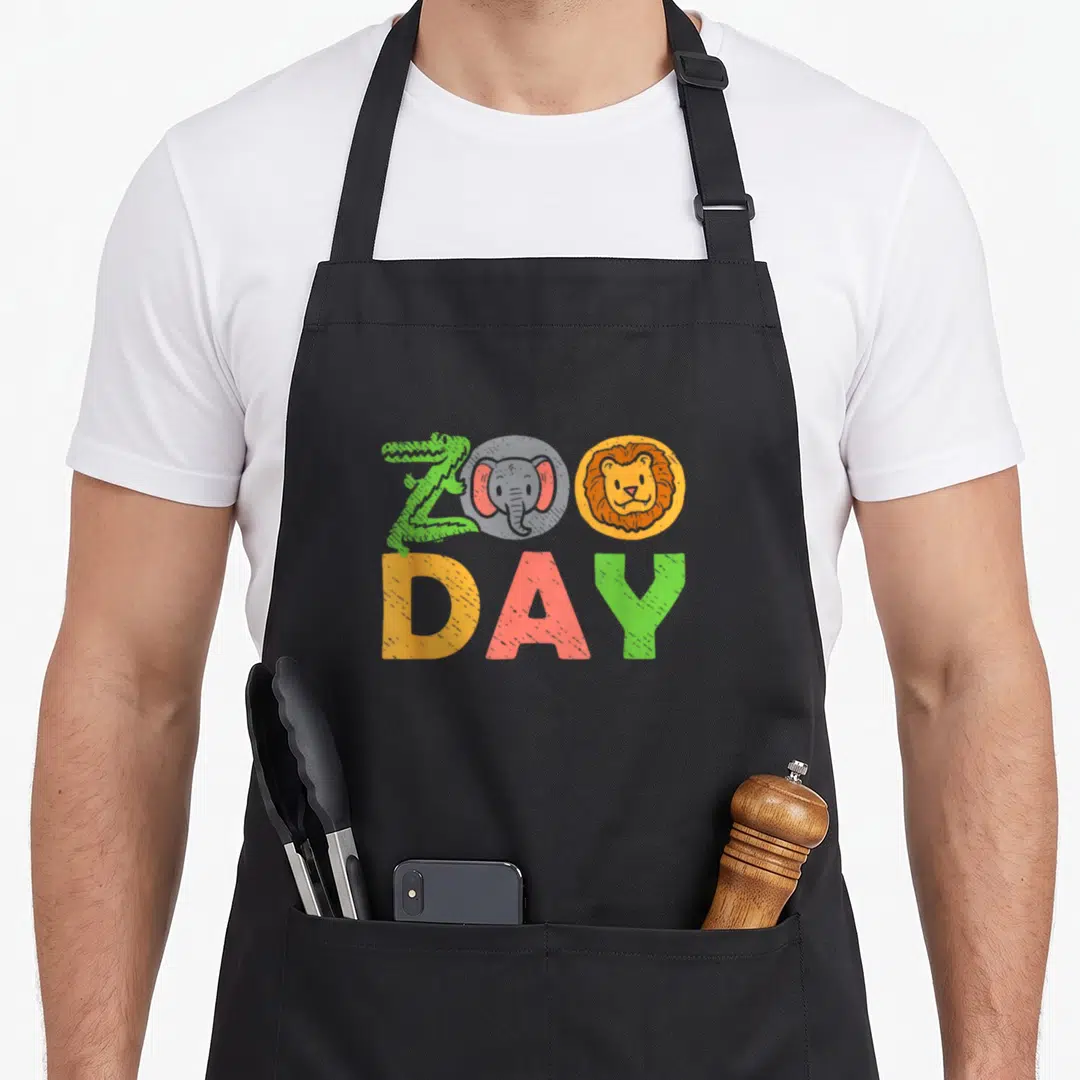 Visitor family aprons - Zoo Day text with crocodile Z, elephant and lion circles in green grey yellow orange red — shown on a black cotton canvas apron against a white background
