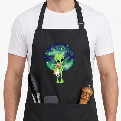 Alien cat apron - Green alien holding orange tabby cat in front of circular blue and green galaxy background — shown on a black cotton canvas apron against a white background
