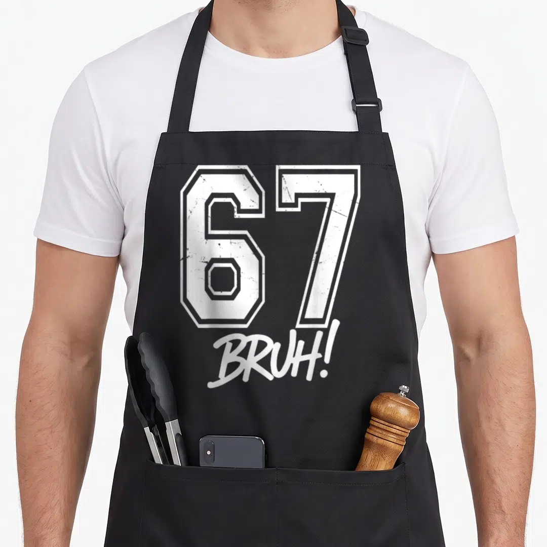Six seven bruh apron - White outlined 67 with BRUH script below on gray background — shown on a black cotton canvas apron against a white background