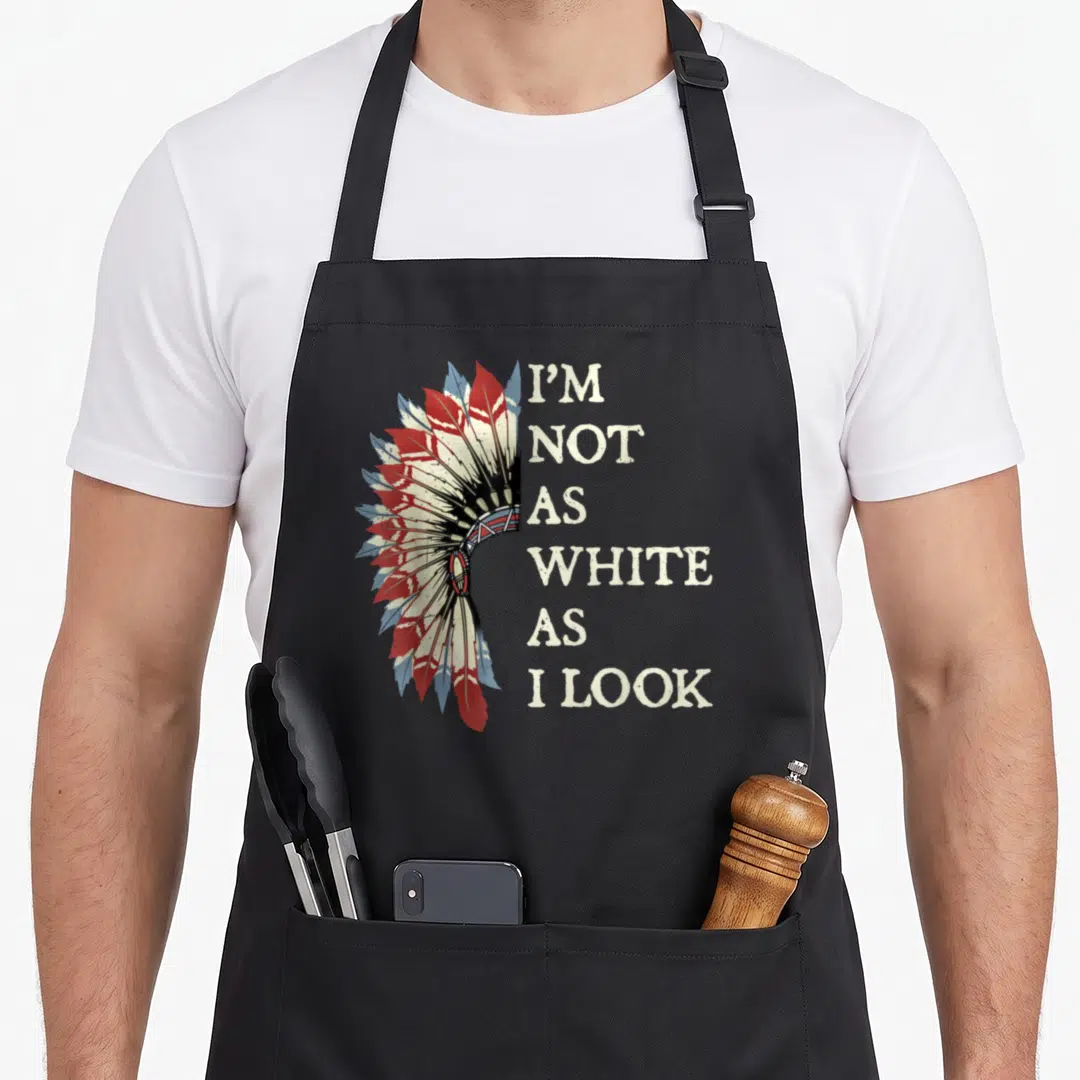 Funny pride apron - I'm Not As White As I Look text next to red and blue headdress graphic — shown on a black cotton canvas apron against a white background