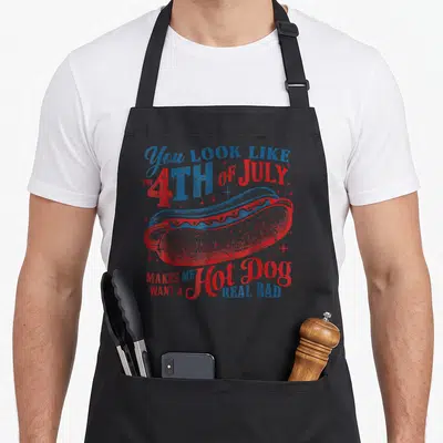 July hot dog apron - Patriotic hot dog illustration with distressed red blue white text and scattered stars — shown on a black cotton canvas apron against a white background