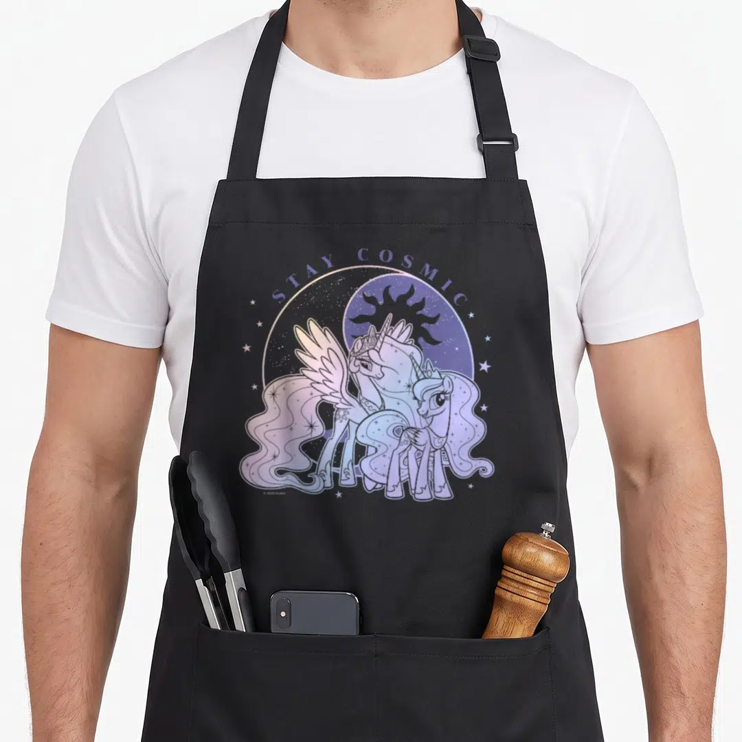 Stay magic apron - Two ponies under STAY COSMIC text with moon sun purple blue pink white — shown on a black cotton canvas apron against a white background