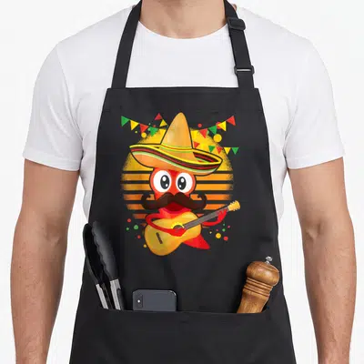 Sombrero peppers lover apron - Cartoon red chili pepper wearing sombrero and mustache playing guitar in front of orange — shown on a black cotton canvas apron against a white background