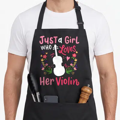 Cute violinist violin apron - White violin silhouette with pink and green flowers and text Just a Girl Who Loves — shown on a black cotton canvas apron against a white background