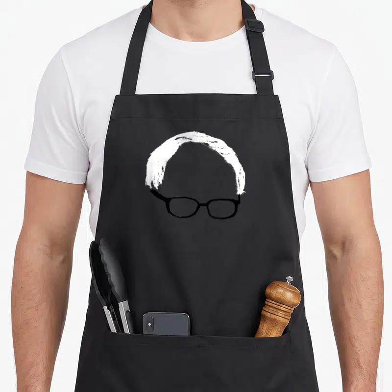 Sander hair apron - Minimalist white hair arch over black glasses on grey background — shown on a black cotton canvas apron against a white background
