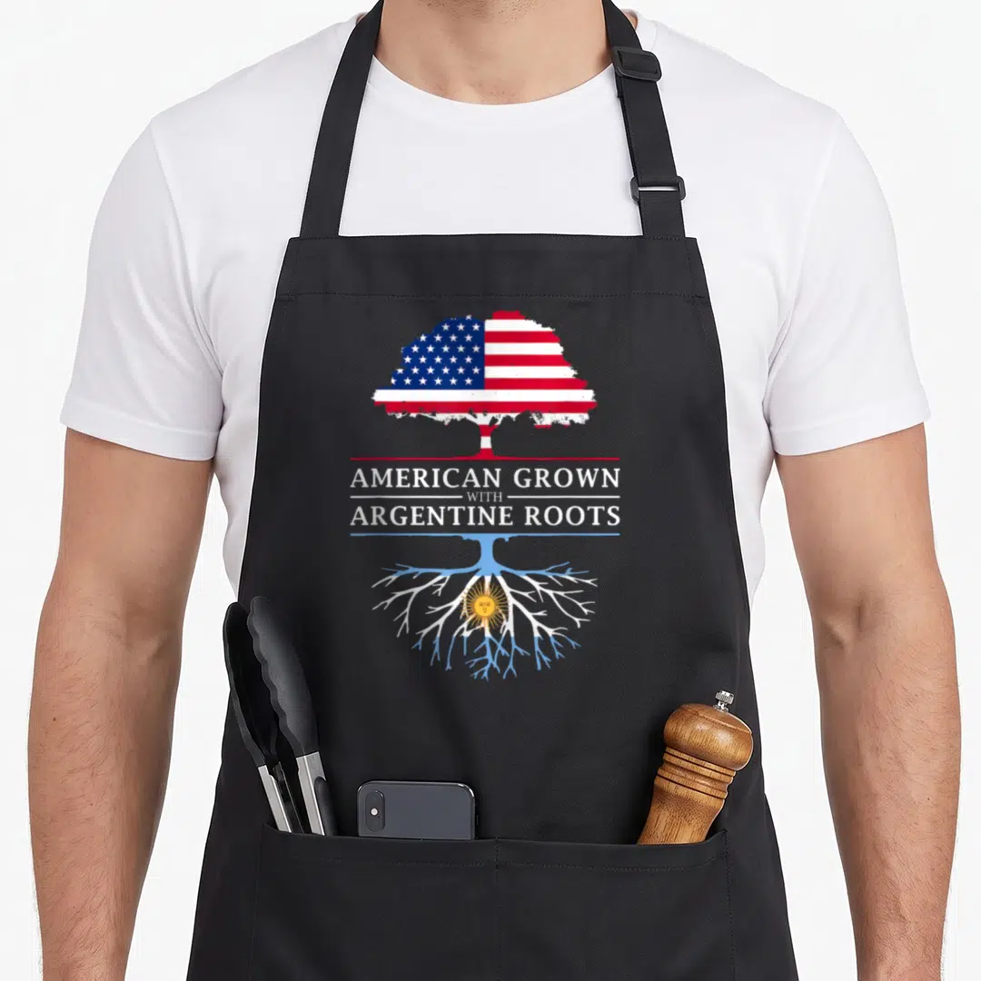 Grown argentine girl apron - Tree with US flag top and Argentina flag bottom roots separated by stacked text — shown on a black cotton canvas apron against a white background