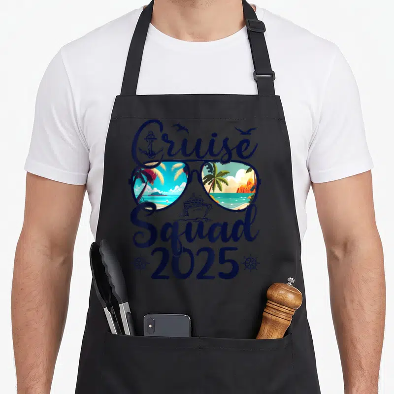 Cruise squad family aprons - Sunglasses with tropical reflections, cruise ship, anchor, and 2025 text in navy and orange — shown on a black cotton canvas apron against a white background