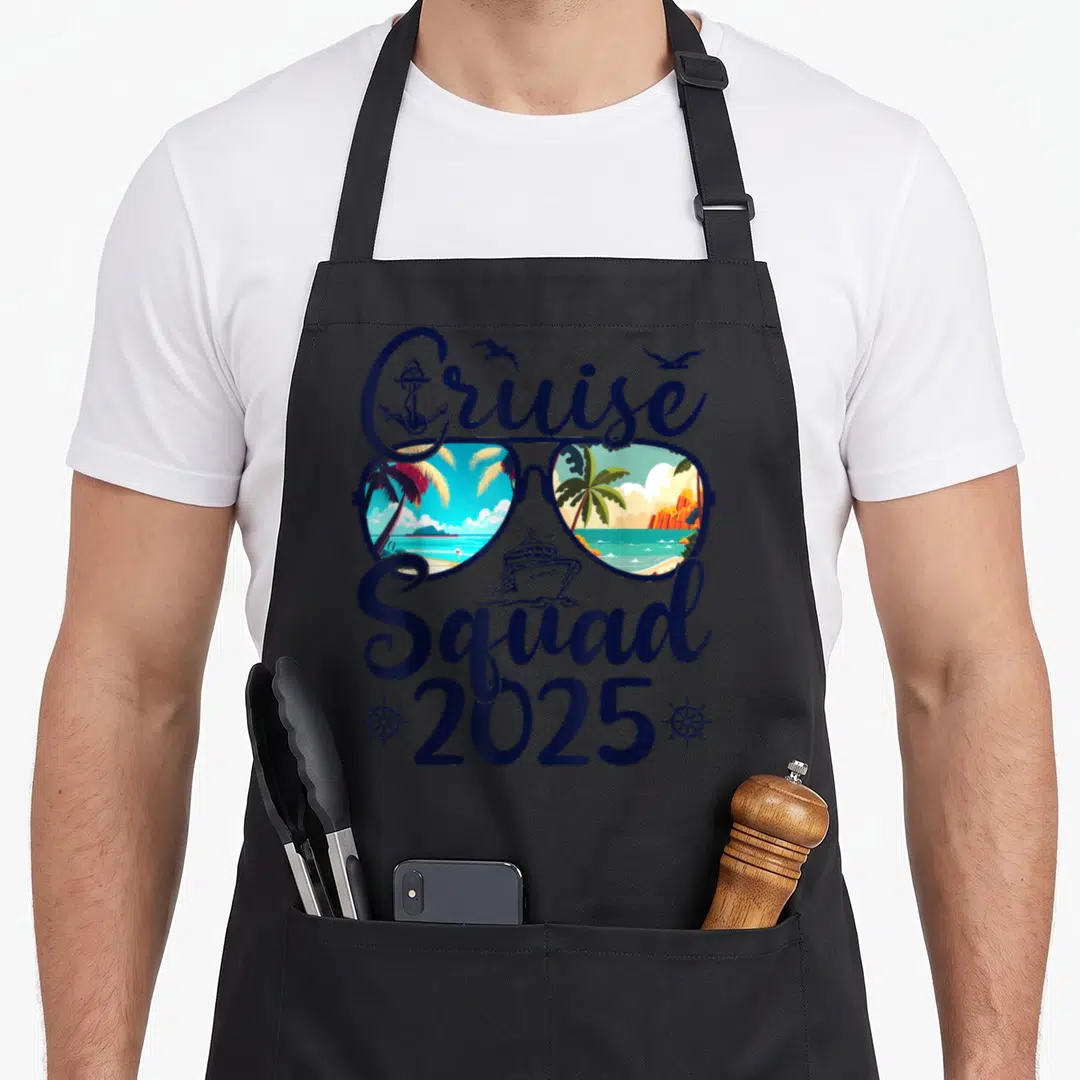 Cruise squad family aprons - Sunglasses with tropical reflections, cruise ship, anchor, and 2025 text in navy and orange — shown on a black cotton canvas apron against a white background