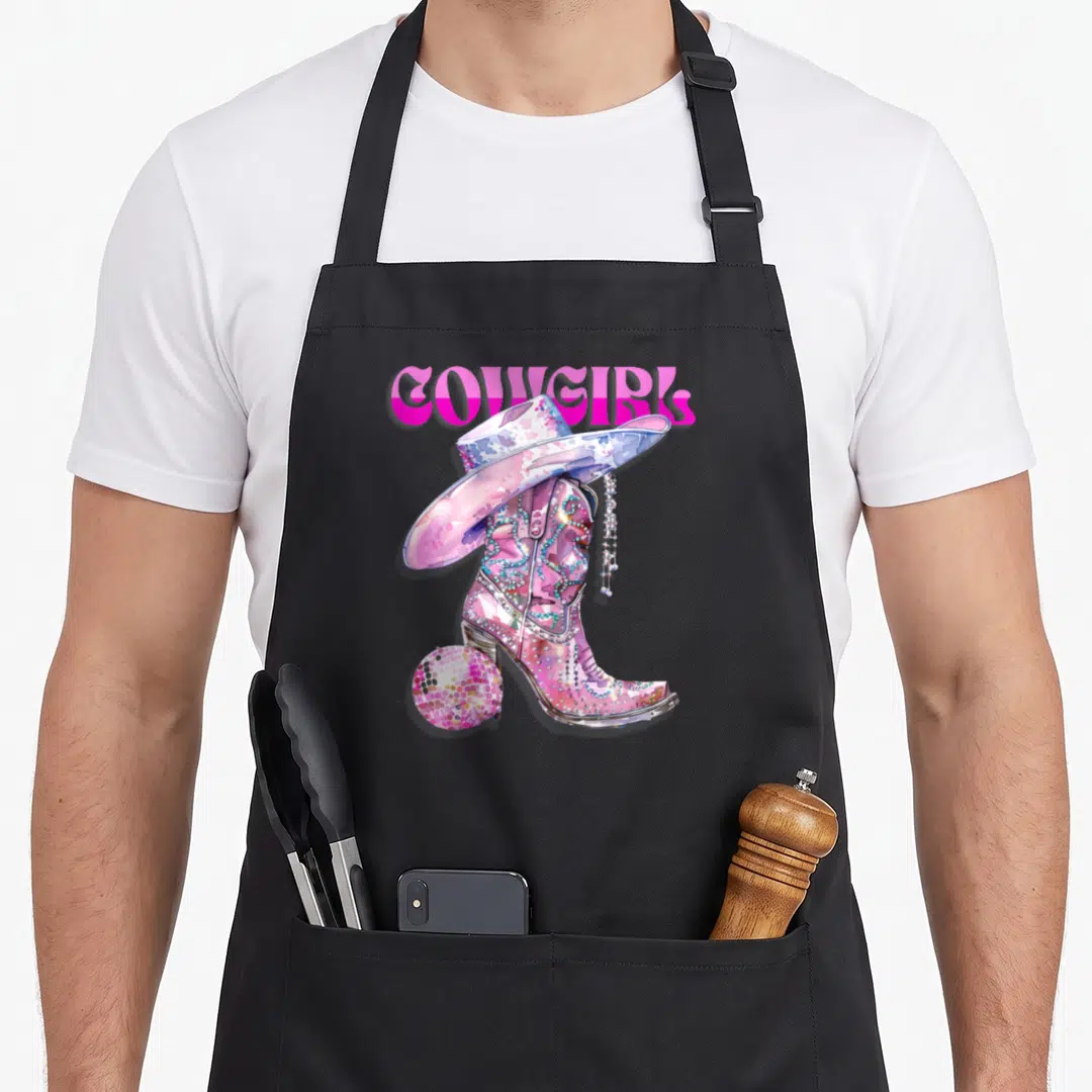 Disco western apron - Pink watercolor cowgirl boot with hat and disco ball heel under COWGIRL text — shown on a black cotton canvas apron against a white background